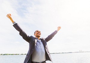 Black businessman cheering with arms outstretched outdoors